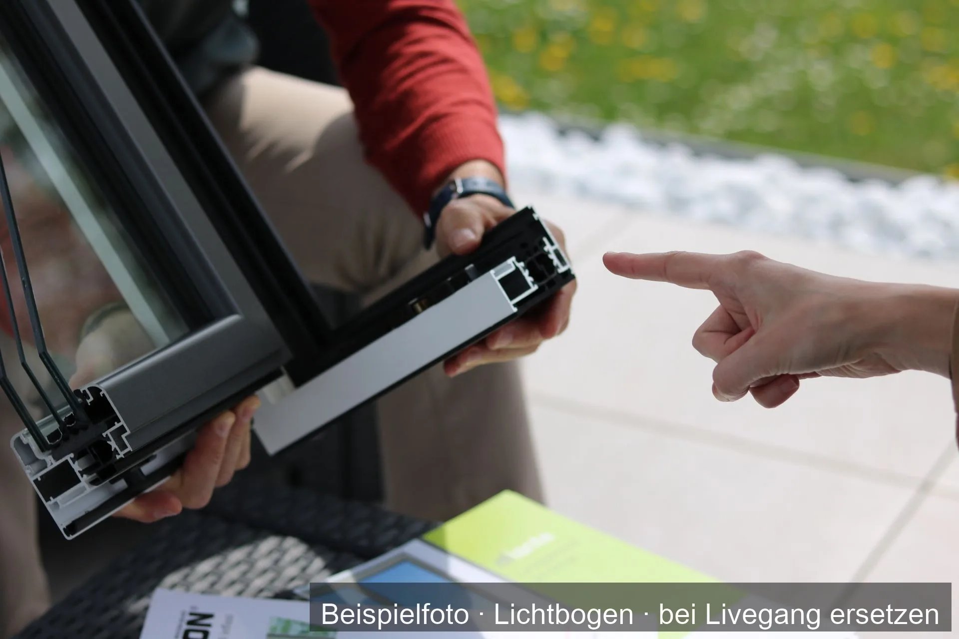 Zwei Personen besprechen ein Fensterprofil aus Aluminium, eine Hand zeigt auf den Rahmen.